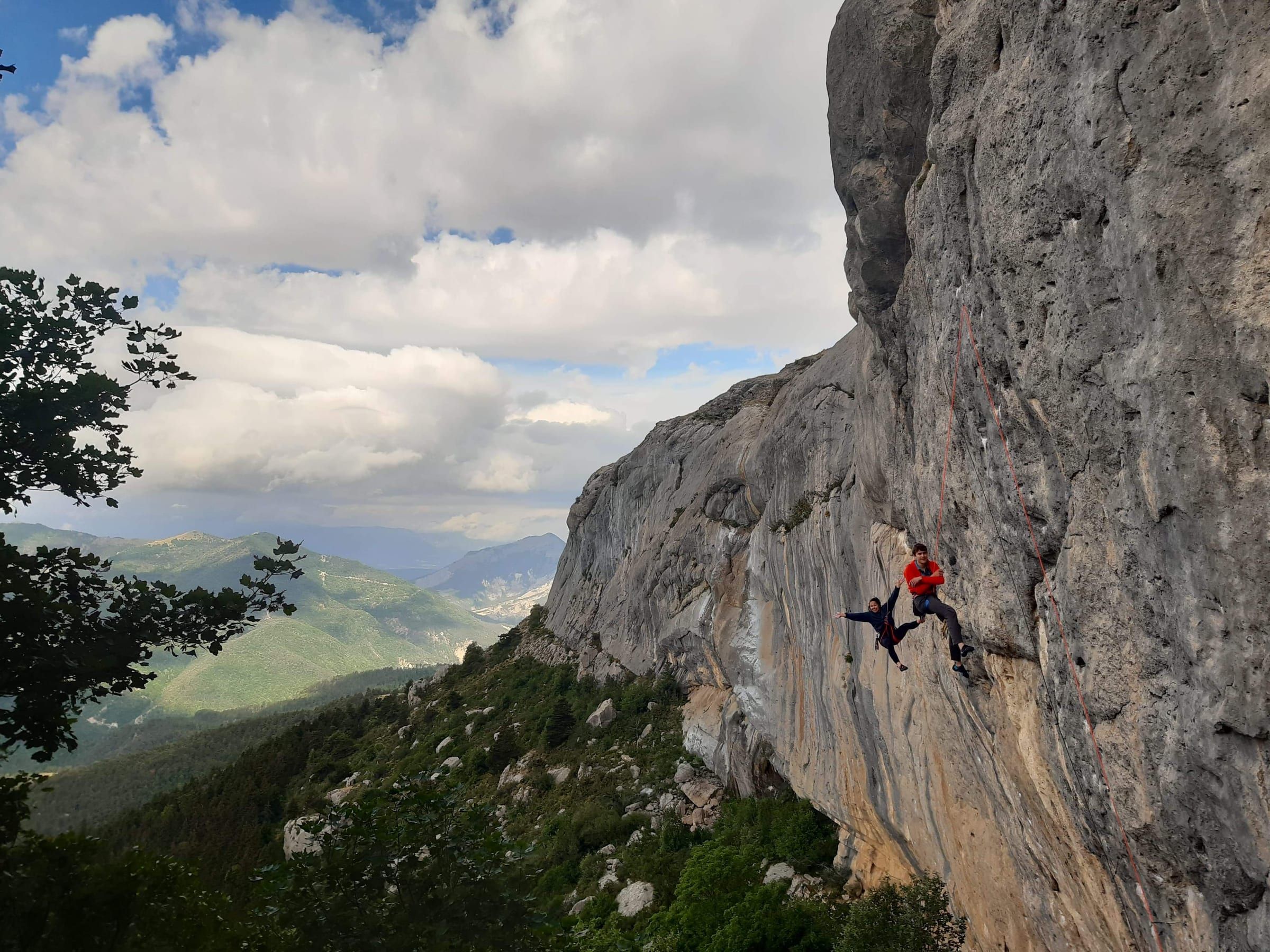 Kitty and a friend hanging off a huge limestone crag above a green valley